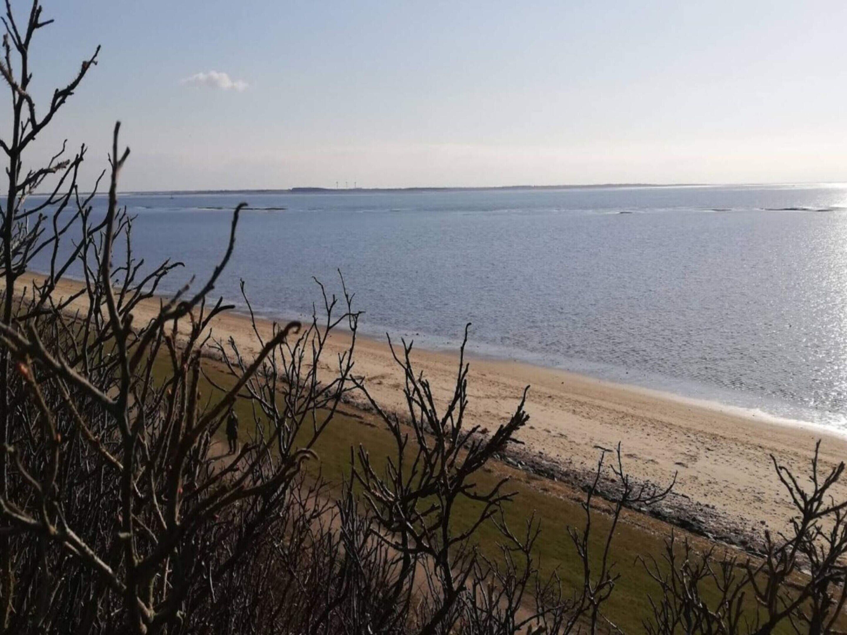 A beach with a clear view of the ocean and a distant shoreline.