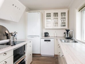 A modern kitchen with white cabinetry, a built-in oven, a dishwasher, and a coffee maker.