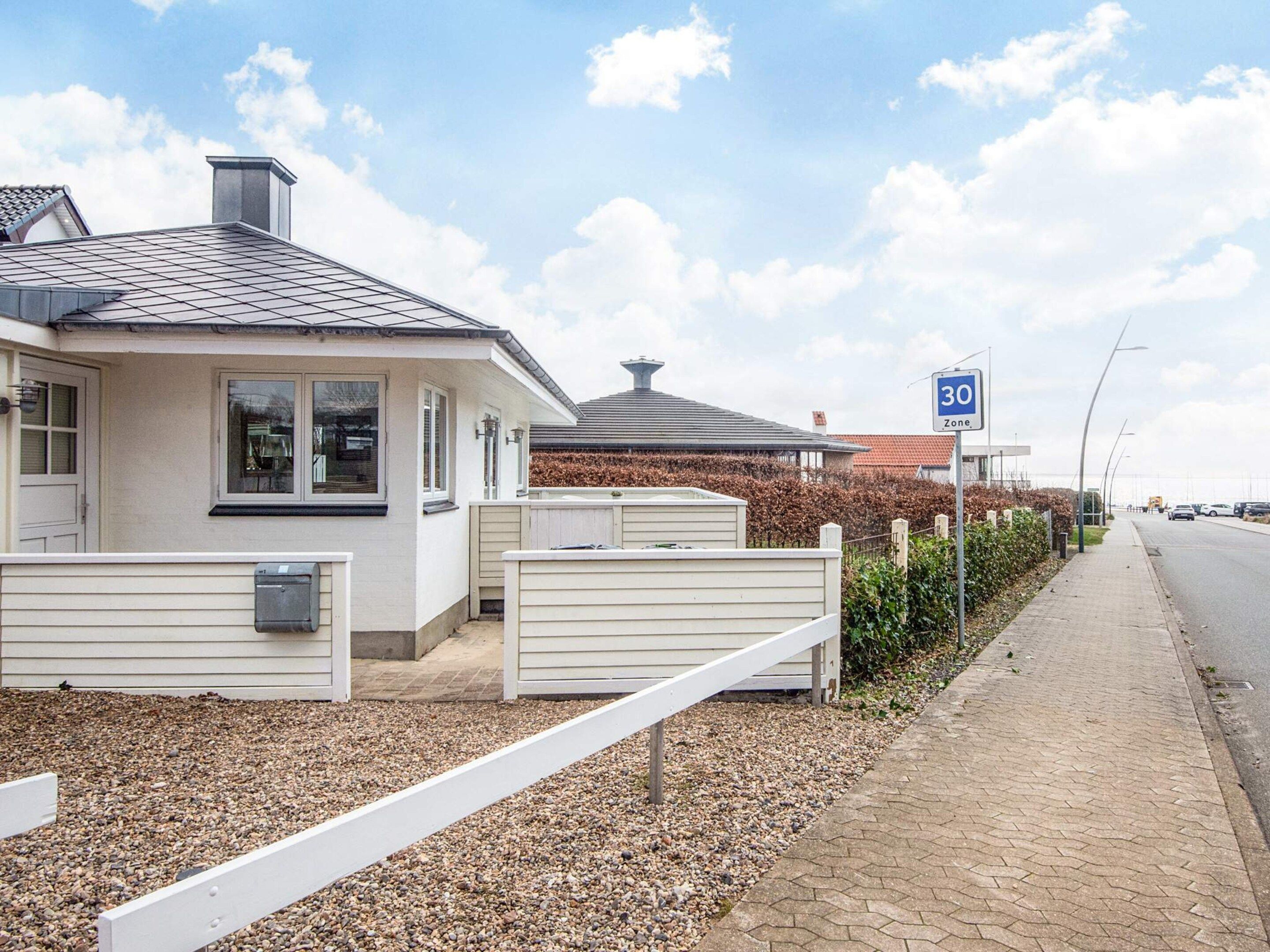 Zona residencial con casas, acera pavimentada y una calle con vehículos.