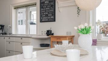 A modern kitchen with a marble countertop, a hanging light fixture, and a decorative sign listing Parisian landmarks.