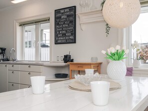 A modern kitchen with a marble countertop, a hanging light fixture, and a decorative sign listing Parisian landmarks. - 5 Star Holiday Home in Esbjerg V (Esbjerg)