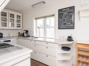 A modern kitchen with white cabinetry, a built-in stove, a sink, and a window with blinds. - 5 Star Holiday Home in Esbjerg V (Esbjerg)