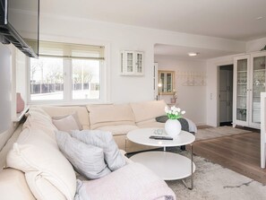 A living room with a beige sofa, a round coffee table, and a cabinet with glass doors. - 5 Star Holiday Home in Esbjerg V (Esbjerg)