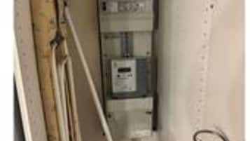 A narrow hallway with a utility panel, a mop, and a bucket.