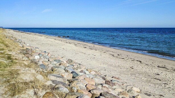 A beach with a rocky shoreline and calm sea. - 9 Person Holiday Home in Otterup-by Traum (Otterup)
