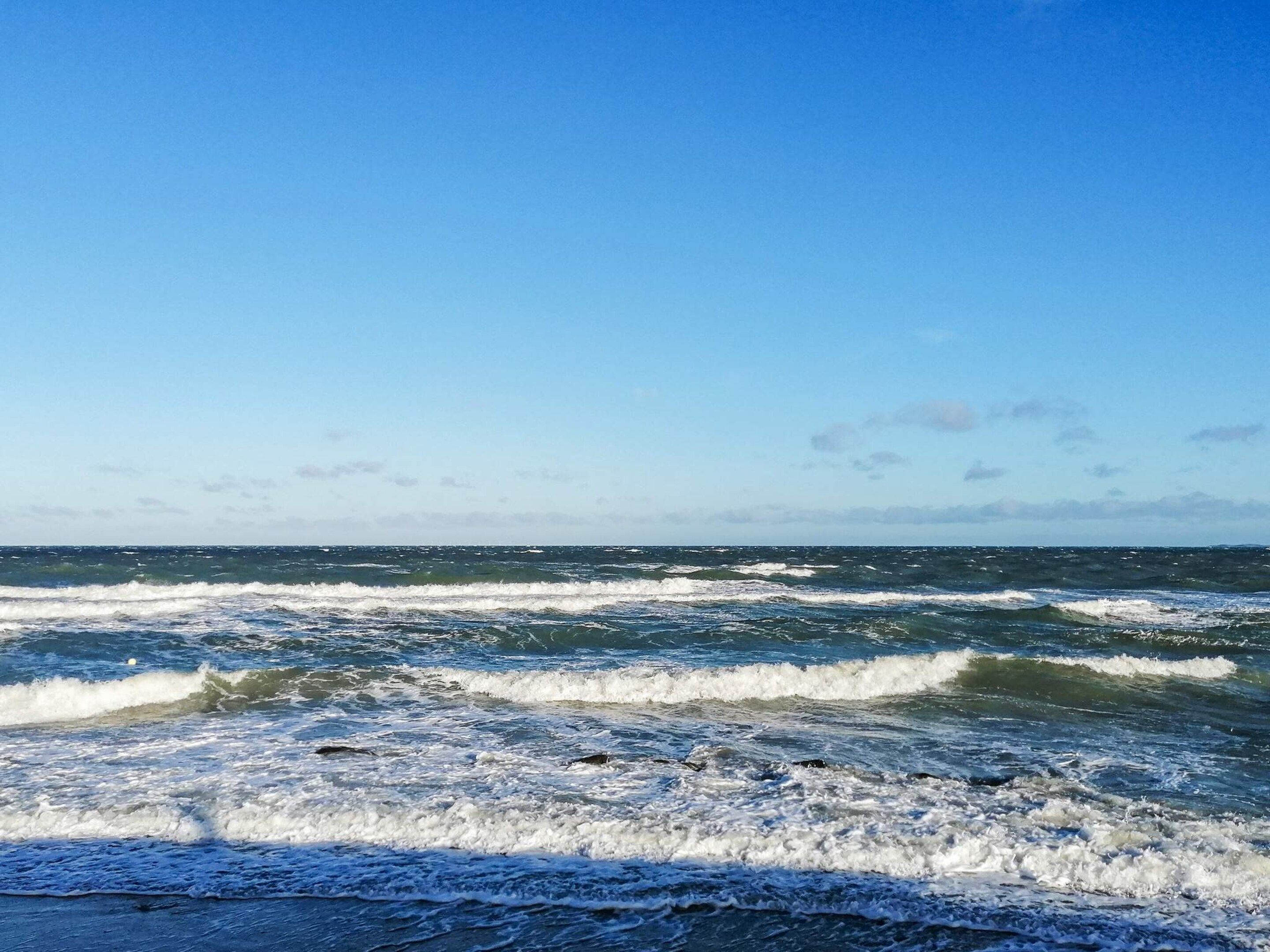 A beach with waves and a clear sky.