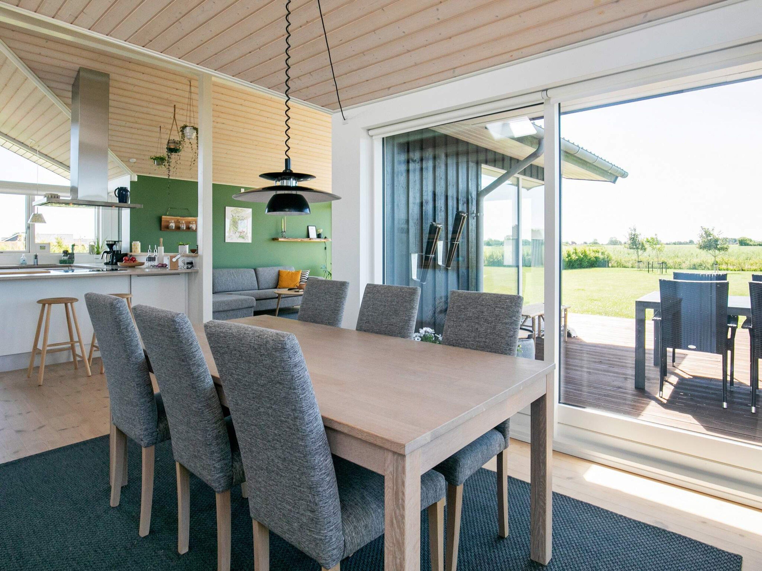 Une cuisine moderne dotée d’un grand îlot central, de chaises à revêtement gris et d’une table à manger.