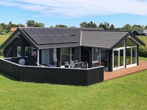 A modern house with a large glass extension, a covered outdoor area, and a sloped roof.
