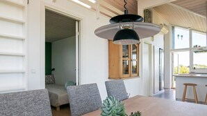 A modern dining area with a wooden table, grey upholstered chairs, and a hanging pendant light. - 9 Person Holiday Home in Otterup-by Traum (Otterup)