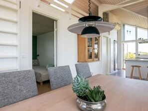 A modern dining area with a wooden table, grey upholstered chairs, and a hanging pendant light. - 4 Star Holiday Home in Otterup (Otterup)