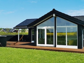 A modern house with a large glass extension, a wooden deck, and a sloped roof.