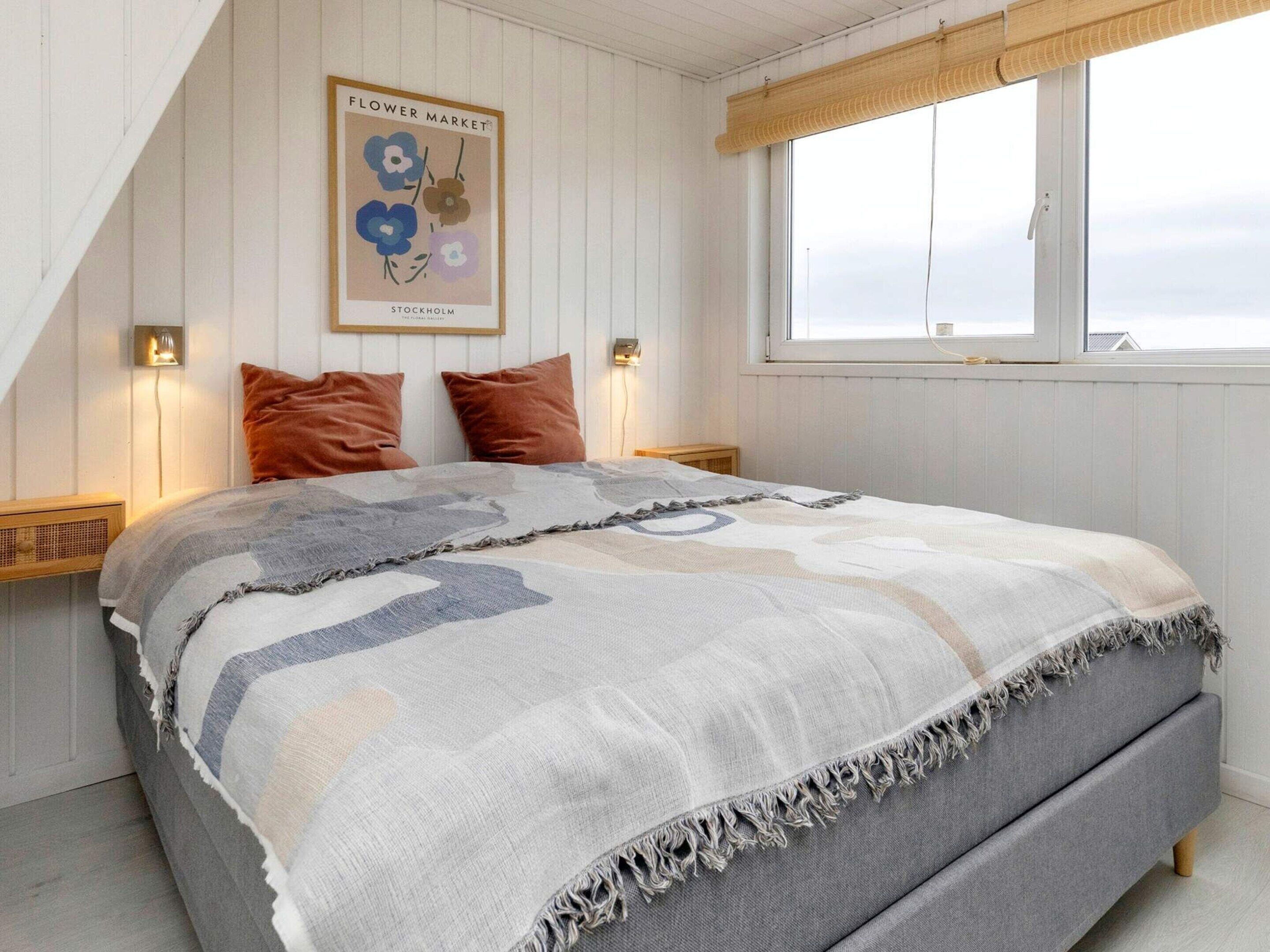 Ein Schlafzimmer mit einem Bett, zwei Kissen, einem Wandposter und einem Fenster mit Blick.