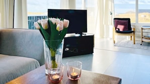 A modern living room with a flat-screen TV, a sofa, a coffee table with candles, and a vase of flowers. - 8 Person Holiday Home in Hjorring (Hjørring)