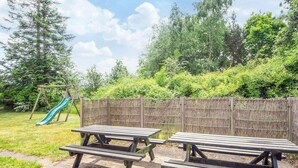 An outdoor picnic area with two wooden picnic tables and a children's slide. - 4 Star Holiday Home in Orsted (Ørsted)