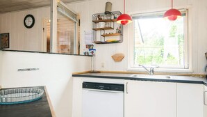 A kitchen with white cabinets, a dishwasher, a window with a view, and red pendant lights. - 4 Star Holiday Home in Orsted (Ørsted)
