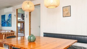 A wooden dining table with chairs, a green teapot, and a bench with black cushions. - 4 Star Holiday Home in Orsted (Ørsted)