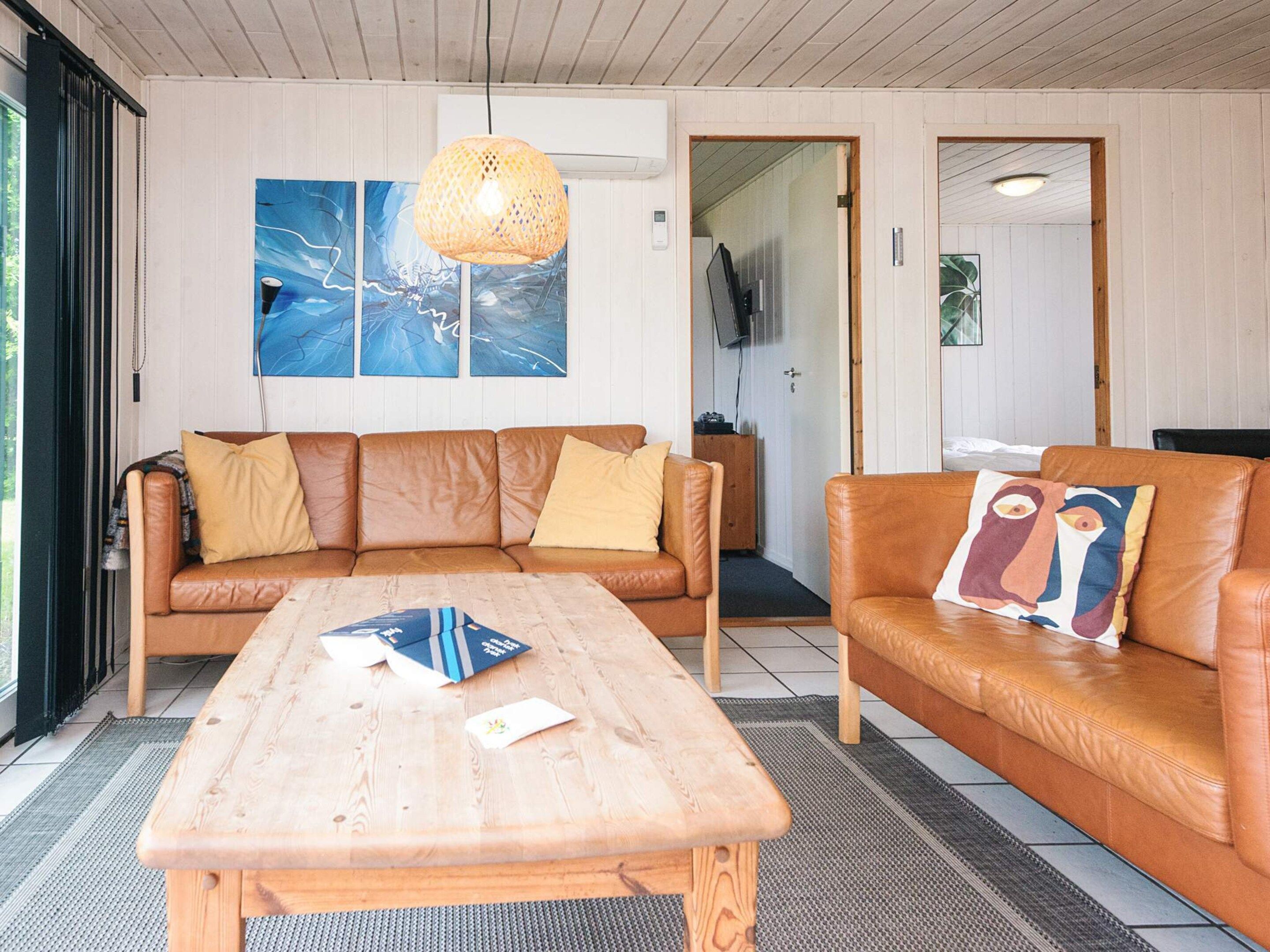 A living room with a wooden coffee table, two brown leather sofas, and a large abstract painting on the wall.