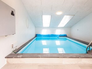 Una piscina con borde de azulejos, una cubierta azul y una escalera de metal.