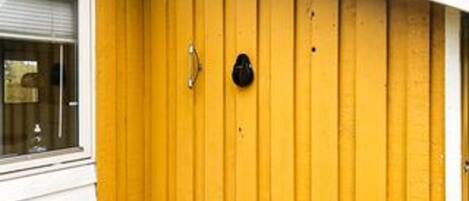 A yellow door with a round black handle and a small peephole.