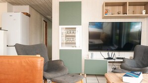A living room with two grey armchairs, a wooden coffee table, a television, and a white refrigerator. - 4 Star Holiday Home in Orsted (Ørsted)