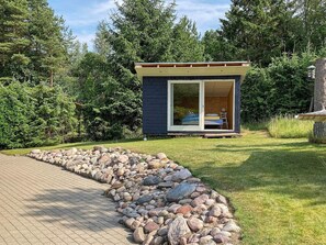 A small cabin with a sliding glass door, a bed, and a chair outside. - 4 Star Holiday Home in Ebeltoft (Ebeltoft)
