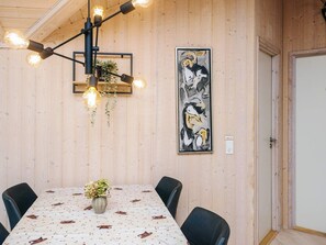 A dining area with a table set for four, a hanging light fixture, and a framed artwork on the wall. - 4 Star Holiday Home in Ebeltoft (Ebeltoft)