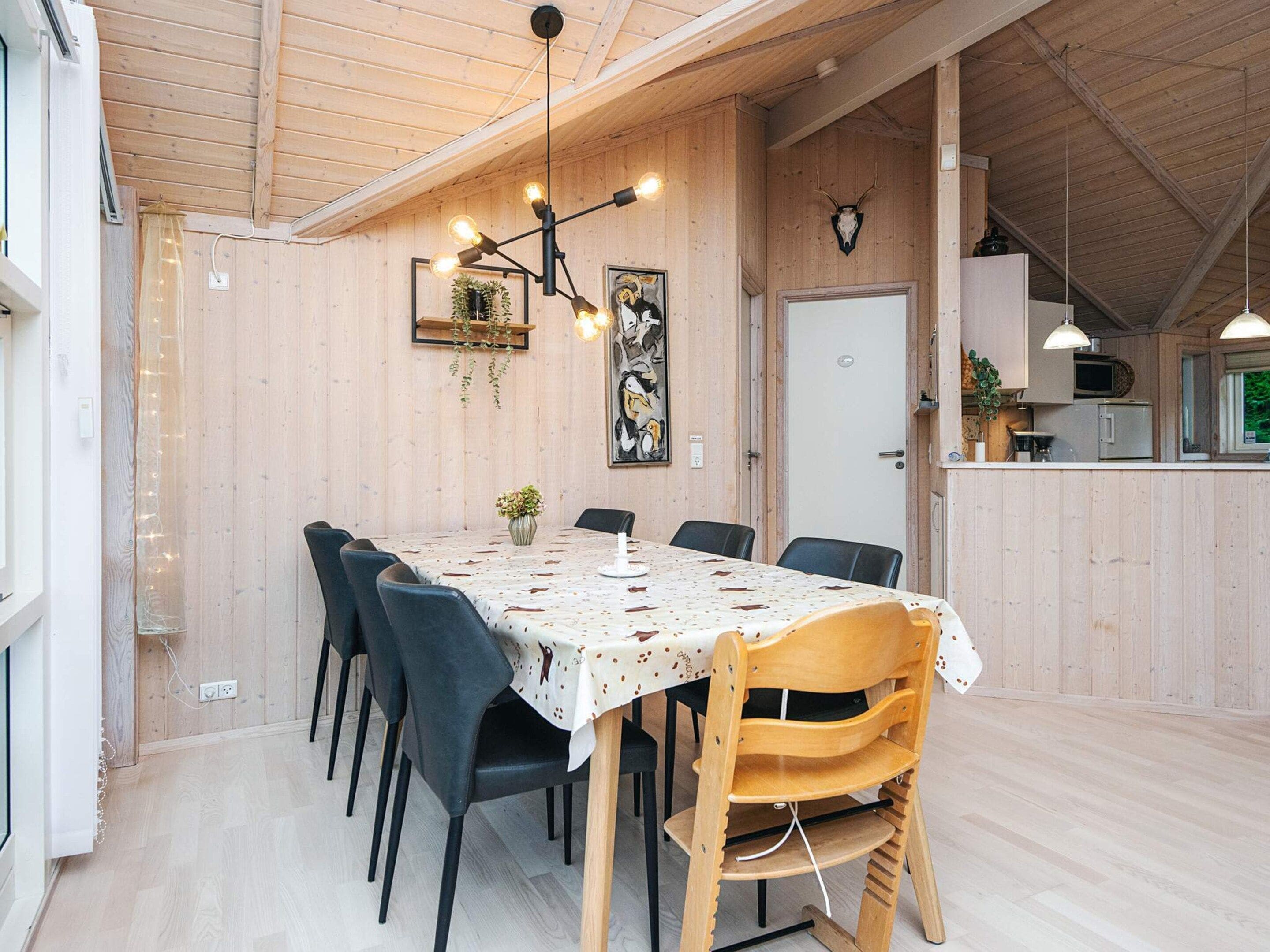 A dining area with a wooden table, chairs, and a chandelier.