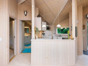 A wooden interior with a kitchen area, including cabinets, a microwave, and pendant lights. - 4 Star Holiday Home in Ebeltoft (Ebeltoft)
