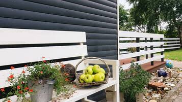 A bench with a basket of green apples and a potted plant with red flowers.