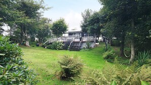 A garden with a wooden bridge leading to a house with a white exterior and a staircase. - 5 Person Holiday Home in Thyholm (Thyholm)