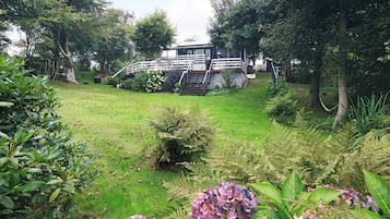 A garden with a wooden bridge leading to a house with a white exterior and a staircase.