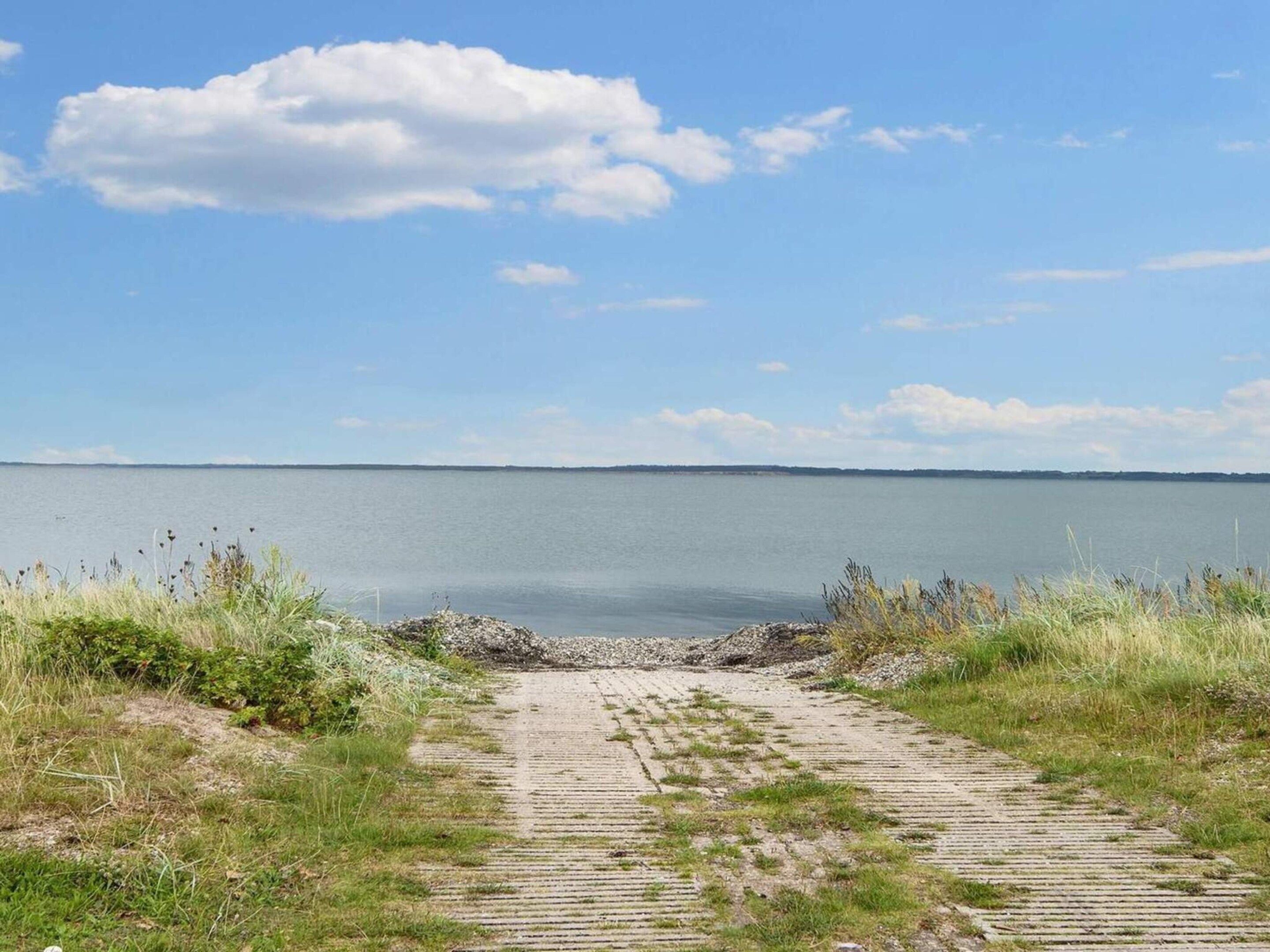 Un sentier qui mène à un plan d’eau, avec un ciel dégagé au-dessus.