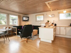 A compact living space with a kitchenette, a dining area, and a seating area with a television.