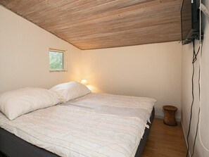 A bedroom with a wooden ceiling, a bed with white bedding, a bedside lamp, a small window, and a wall-mounted TV. - 5 Person Holiday Home in Thyholm (Thyholm)