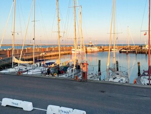 Un puerto deportivo con varios veleros amarrados, cielo despejado y una superficie acuática tranquila.