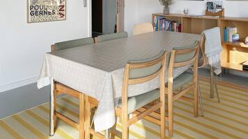 A dining area with a table and chairs, a bookshelf, and a lamp.