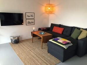 A living room with a sofa, a coffee table, a TV mounted on the wall, and a lamp. - 4 Star Holiday Home in Thyboron (Thyborøn)