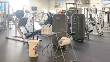A gym with various exercise equipment, a large mirror, and a motivational poster on the wall.