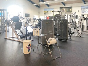 A gym with various exercise equipment, a large mirror, and a motivational poster on the wall.