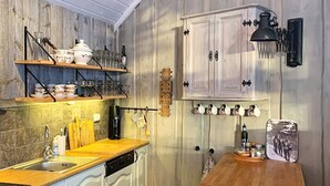 Una cocina con armarios blancos, encimera de madera y una lámpara colgante.