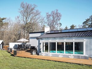 A modern building with a large glass window, a wooden deck, and a solar panel roof. - 5 Star Holiday Home in Nexo (Nexø)