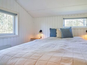 A bedroom with a large bed, two bedside lamps, and two windows. - 5 Star Holiday Home in Nexo (Nexø)