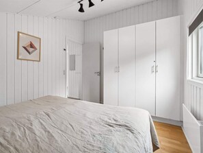 A bedroom with a bed, white wardrobe, and a framed picture on the wall.