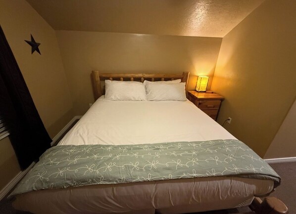 A single bed with a wooden headboard, a bedside lamp, and a star decoration on the wall. - Welcome to Serenity Hills Zion , Sleeps 10 + (Glendale)