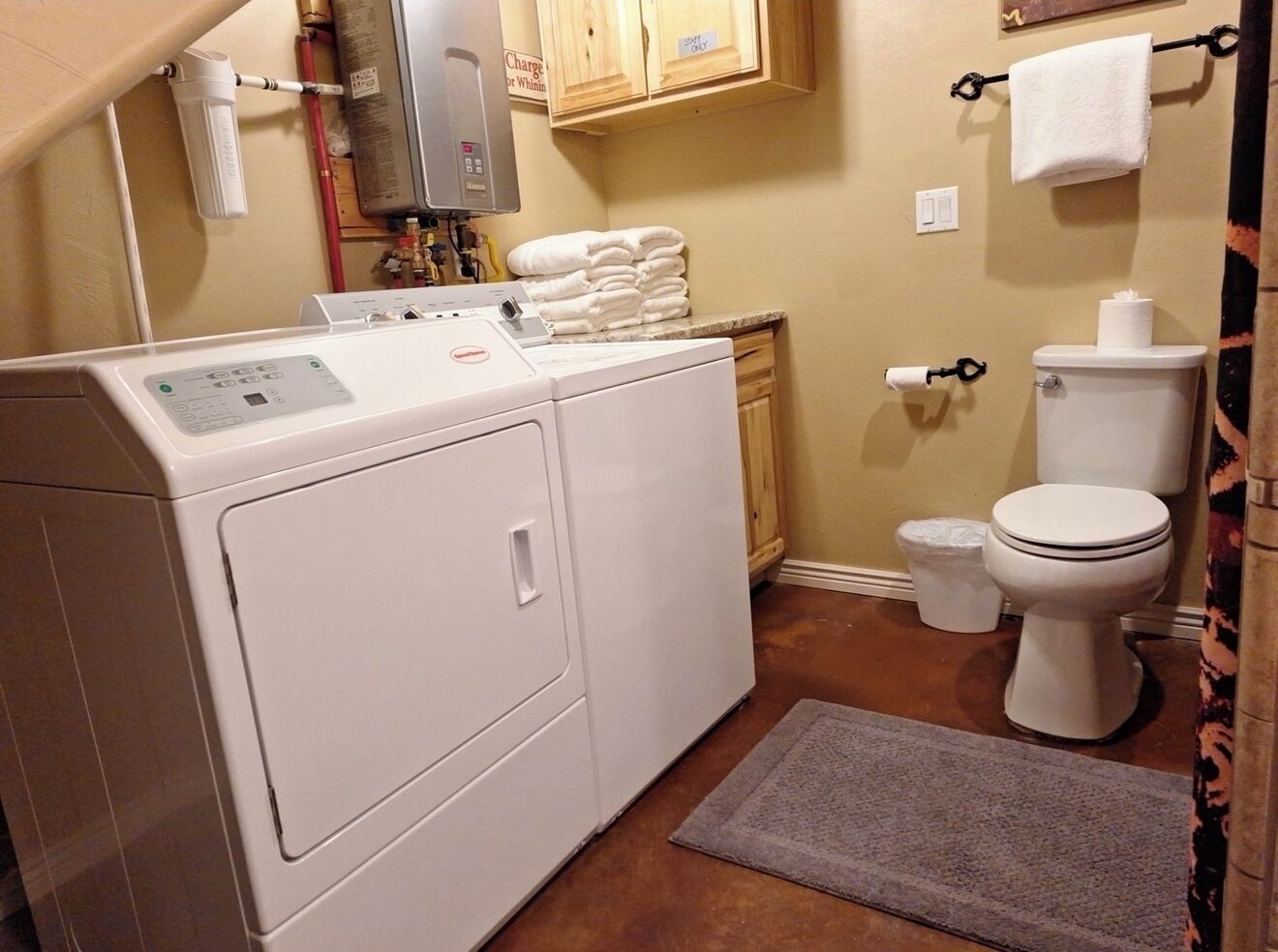 Ein kleiner Hauswirtschaftsraum mit einer Waschmaschine und einem Trockner, einer Toilette und einem Teppich.