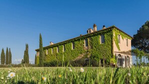 A large, ivy-covered building with multiple windows and a garden in the foreground. - Luxury villa at 15 minutes driving from the seaside (Gavorrano)