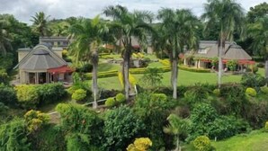Resort com vários edifícios, palmeiras e jardins bem cuidados.