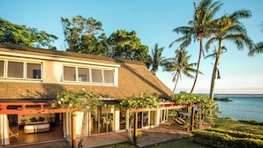 Uma casa moderna com um pátio, grandes janelas e vista para o oceano.