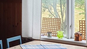 A room with a wooden table, a window with a view of trees, and a decorative screen. - 4 Person Holiday Home in Jarvso (Jarvso)