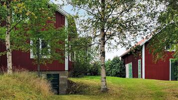 A red barn with a green door, surrounded by trees and grass.